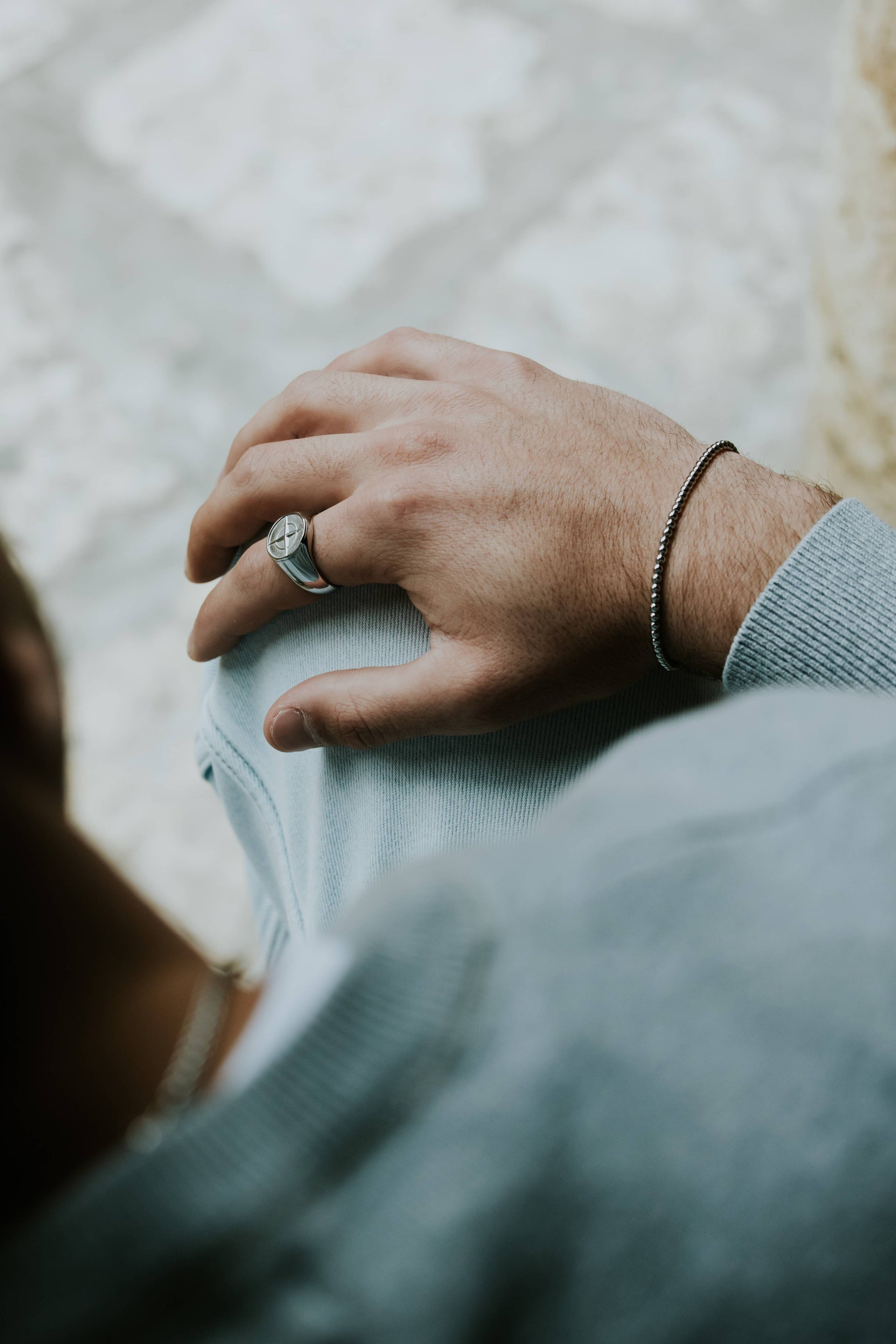 יד גברית עם צמיד חרוזי כסף וטבעת, עיצוב אלגנטי ועדין, מתאים ללבישה יומיומית ואירועים.